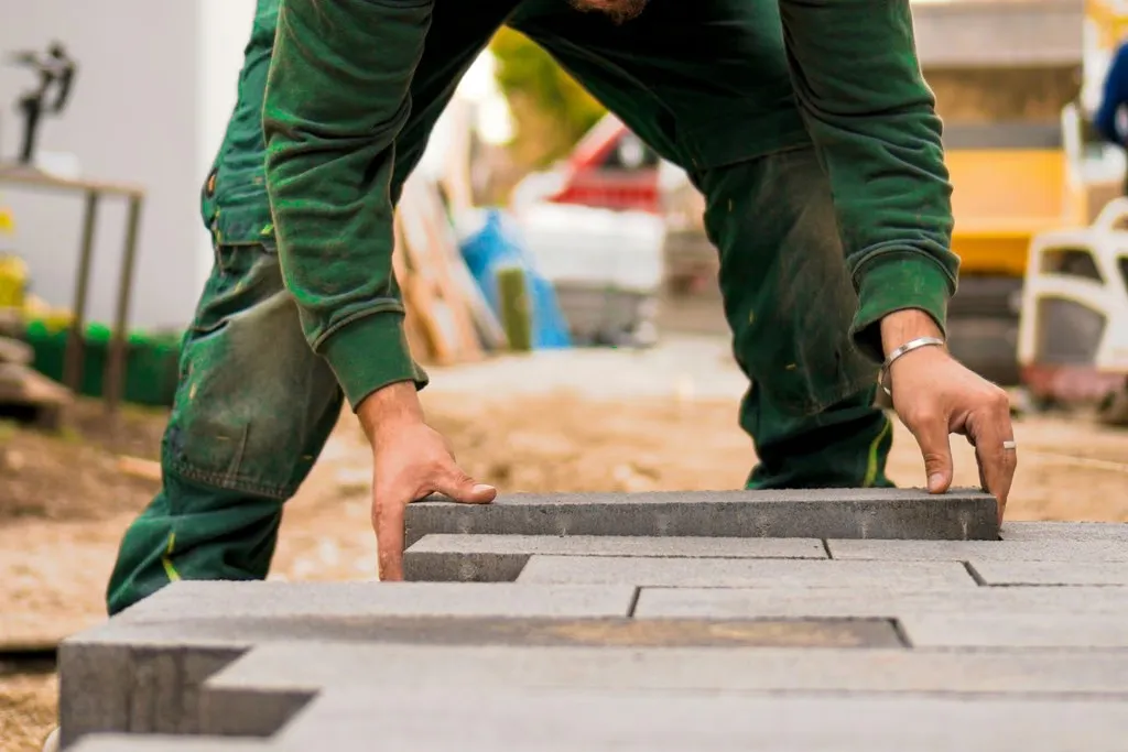A man in a green shirt laying bricks