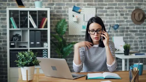 A woman sitting at a desk talking on a cell phone